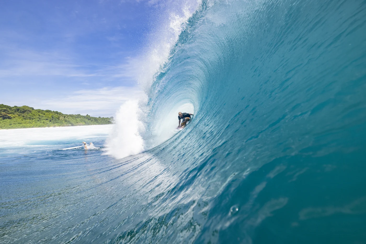 A surfer inside a clear blue Mentawai barrel